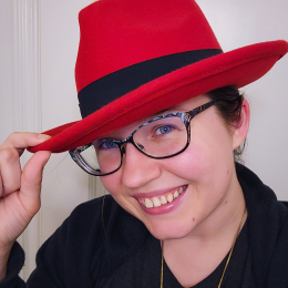 Emilie Nouveau head shot of her wearing a red fedora
